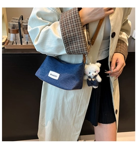 Λεπτομέρεια τσάντας ώμου denim blue με γούρι αρκουδάκι και υφαντή λεπτομέρεια ετικέτας