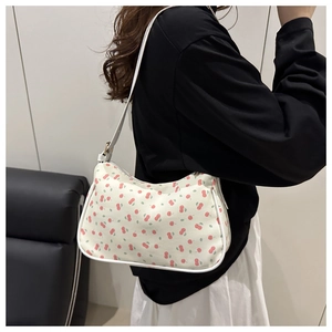 Detail der weißen Canvas-Achseltasche mit rotem Kirschdruck und schmalem Schultergurt