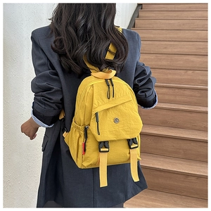 Detailopname van gele nylon crossbodytas met gespsluiting gedragen door een model