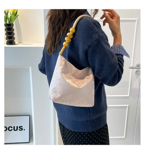 Détail du tissu jacquard floral rose et de la bandoulière en perles de bois du sac