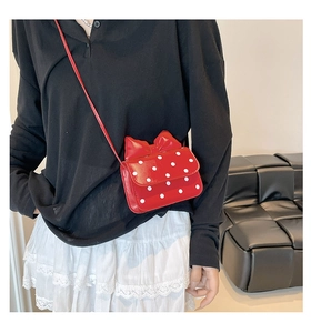 Detailed view of red polka dot crossbody bag with large bow and glossy finish