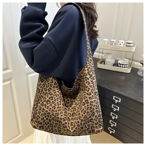 Macro detail of large leopard print canvas tote bag with soft texture and wide shoulder strap