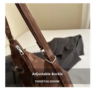 Detail of silver adjustable strap buckle on a vintage brown faux leather shoulder bag