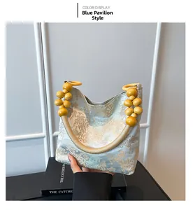 Détail d'un sac à main en soie bleue avec broderie dorée et poignée en perles jaunes