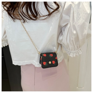 Detail of mini strawberry print crossbody bag with gold chain and snap button closure