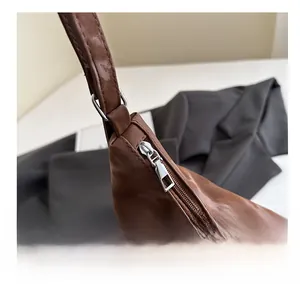 Macro detail of brown leather bag showing smooth silver zipper and stitching quality