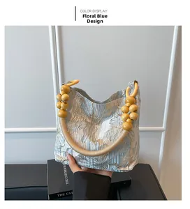 Détail du sac jacquard bleu clair avec poignée décorative en perles de bois jaunes