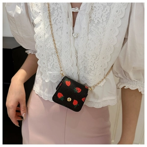 Détail du mini sac bandoulière noir avec imprimé fraise et fine chaîne dorée