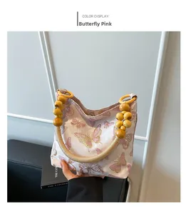 Détail d'un sac en tissu rose avec motif papillon et poignée en perles de bois