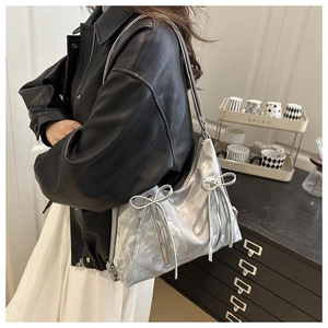 Detail of silver metallic tote bag featuring bow accents and zipper on shoulder strap