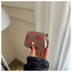 Détails de texture du mini sac fraise en similicuir marron grainé avec fine chaîne dorée