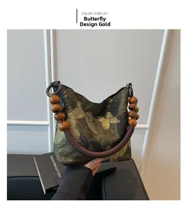 Détail du sac à main vintage avec motif papillon doré et poignées en perles de bois