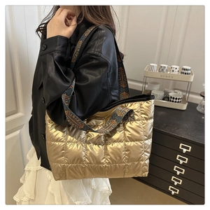Détail d'un sac cabas doré matelassé avec bandoulière rétro colorée porté par un mannequin