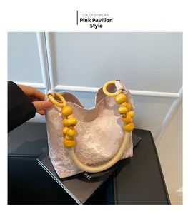 Détail d'un sac à main jacquard rose avec motifs de pavillon et poignées en perles de bois