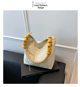 Détail du sac beige à motif de feuilles avec anses uniques en perles de bois jaunes