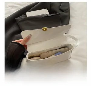 Top view of white patent leather shoulder bag interior with gold lock and daily essentials
