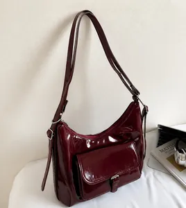 Close-up of wine red patent leather hobo bag with adjustable strap and silver metal buckle