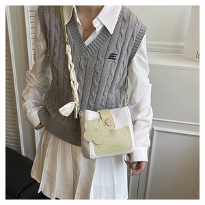 Detail of crossbody bucket bag with cream and green contrast and floral charm