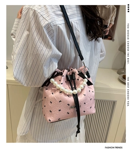 Detail van roze emmertas met parelhandvat en strik, gedragen door een model in stijl