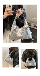 Details der silbernen Metallic-Schultertasche mit Schleifen und Reißverschlüssen