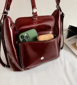 Close-up of deep red glossy leather handbag pocket showing phone and wallet storage