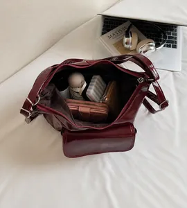Spacious interior of dark red glossy leather shoulder bag showing daily essentials