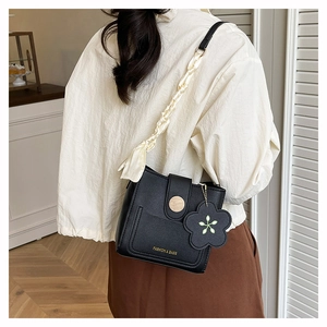 Détail du sac seau noir avec bandoulière en foulard de soie et pendentif fleur