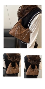 Braune Schultertasche aus Leder mit Reißverschlüssen und Riemen am weiblichen Model