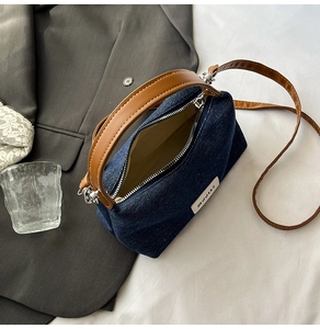 Detailed top view of denim handbag showing interior space and brown leather strap