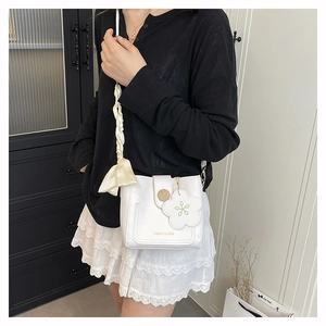 Détail du mini sac seau blanc avec breloque fleur et bandoulière en satin