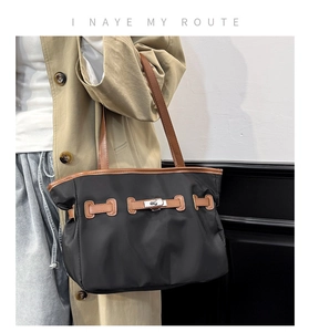 Detail van zwarte nylon draagtas met bruine lederen rand en zilveren metalen sluiting