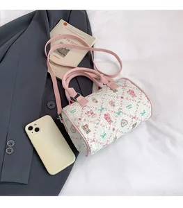 Vue à plat d'un sac tonneau blanc à motifs à côté d'un smartphone pour comparer la taille