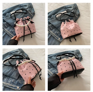 Detailweergave van roze emmertas met strikprint en een elegante parel handgreep