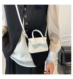 Détail du mini sac blanc en cuir grainé avec sa bandoulière porté par un mannequin en mode