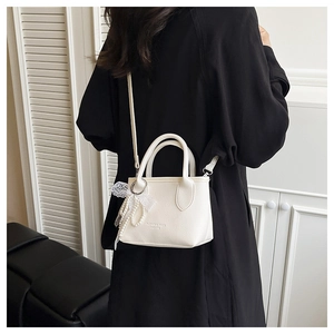 Detailopname van witte crossbodytas met lycheepatroon en parel- en kantdecoratie