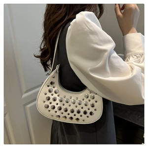 Detail of white crescent hobo bag with silver metallic studs worn by a model