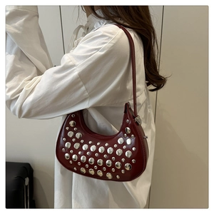 Side view of wine red crescent bucket bag with silver studs on shoulder strap