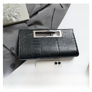 Detail of black crocodile texture handbag with silver metal handle and smartphone for scale