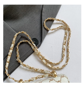 Détail d'un sac à bandoulière en cuir blanc avec motif vintage et chaîne dorée