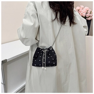 Black drawstring bucket bag with white bow pattern and pearl detail on a model