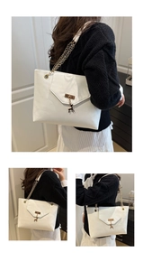 Macro detail of white PU leather tote bag with metal deer pendant and golden chain strap