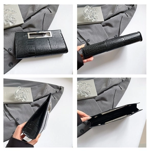 Macro view of black crocodile pattern clutch bag showing metal handle and interior texture