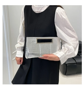 Detail of silver crocodile pattern clutch bag featuring a rectangular metal handle