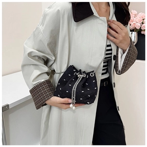 Detail of black drawstring bucket bag with bow embroidery and pearl tassel detail