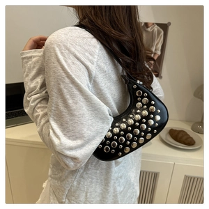 Detail of black crescent moon shoulder bag featuring silver metal studs and punk style