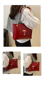 Detail of red glossy tote bag featuring gold chain strap and deer charm on a model