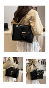 Detail of glossy black faux leather tote featuring a metal lock and gold chain strap