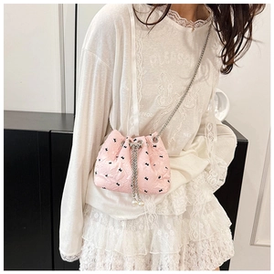 Pink bucket bag featuring black bow patterns and elegant pearl drawstring charms
