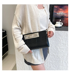 Detail of black crocodile pattern clutch bag with rectangular silver metal handle