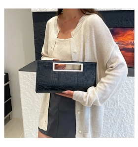 Detail of black crocodile texture leather and rectangular silver metal handle on clutch bag